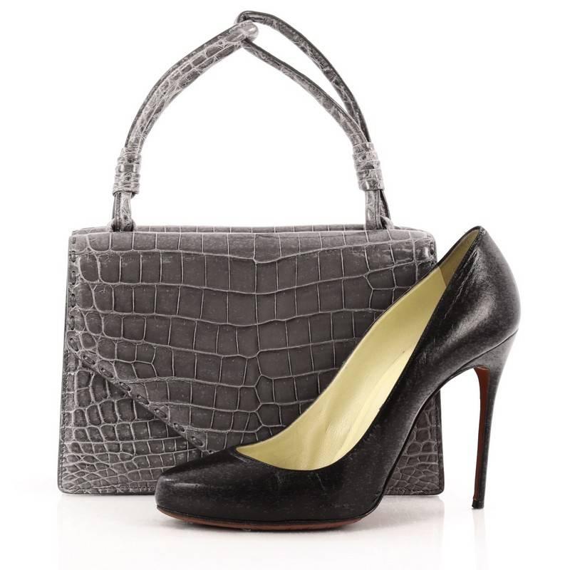 This authentic Bottega Veneta Luxanil Bag Crocodile presented in the brand's 2007 Collection exudes a luxurious, understated look with timeless appeal. Crafted from gray genuine shiny crocodile skin, this stylish bag features rolled top handles with