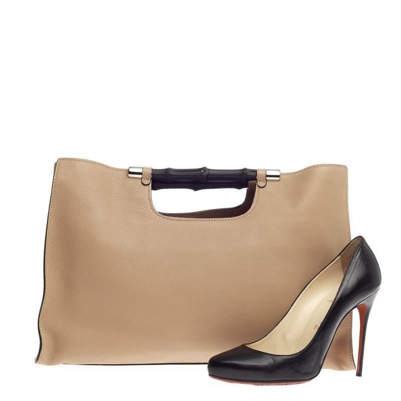 This authentic Gucci Bamboo Daily Tote Leather Wide is a chic, must-have made for everyday use. Crafted from supple nude leather, this simple yet stylish tote features Gucci's signature sturdy lacquered bamboo hand grips, and silver-tone hardware