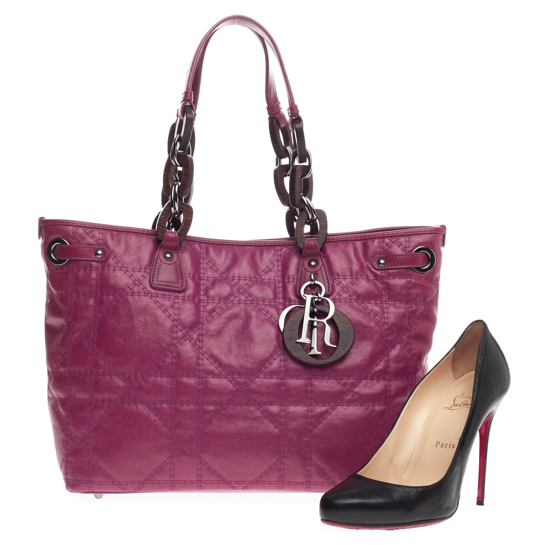 This authentic Christian Dior Panarea Wood Link Tote Cannage Quilt Canvas Medium is a classic for every fashionista. Crafted in magenta pink quilted canvas, this updated chic tote features Dior's signature cannage quilting, dual wooden link straps