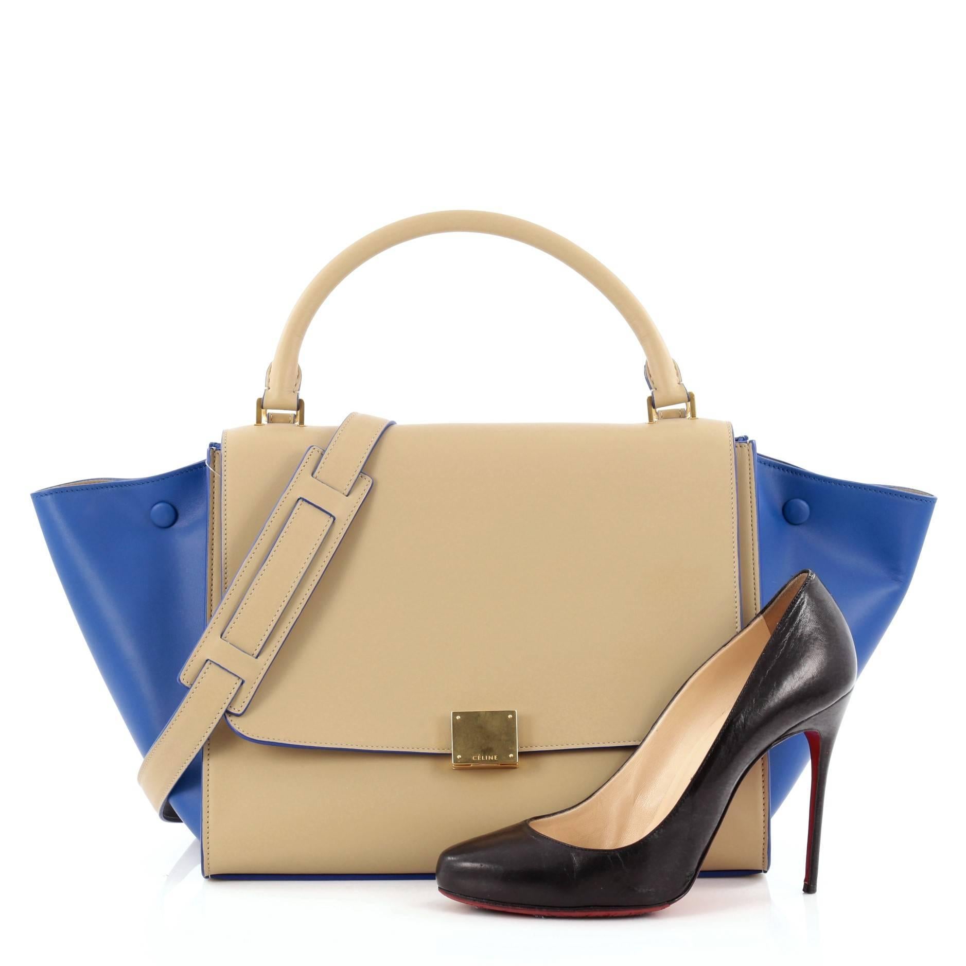 This authentic Celine Bicolor Trapeze Leather Medium is a modern minimalist design with a playful twist in an array of subdued colors. Crafted from beige and blue leather side wings, this classic satchel features rolled top handle, exterior back zip