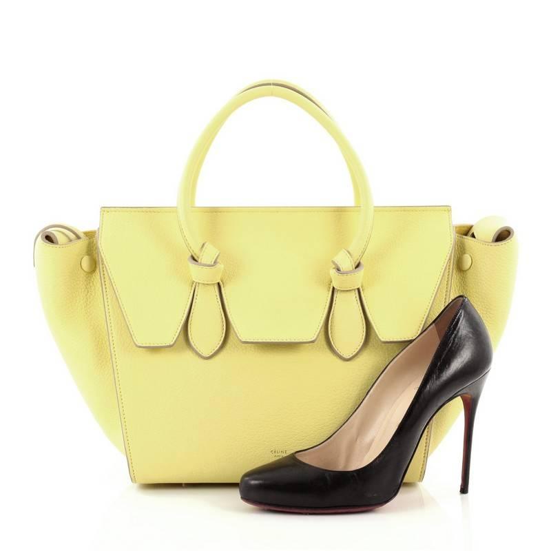 This authentic Celine Tie Knot Tote Grainy Leather Mini presented in the brand's Spring/Summer 2014 Collection is an absolute must-have for serious fashionistas. Crafted from neon yellow pebbled leather, this boxy, chic tote features dual-rolled