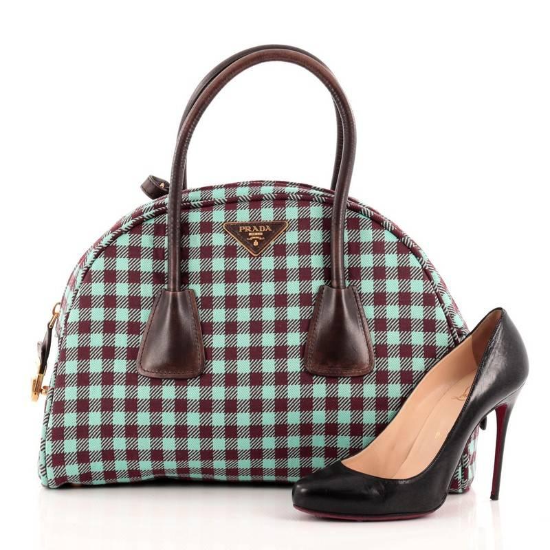 This authentic Prada Vichy Vintage Bowler Jacquard Large is an elegant, innovative fall-ready accessory for every fashionista. Crafted from teal and burgundy jacquard fabric, this chic bag features dual-rolled handles, triangular Prada logo at top
