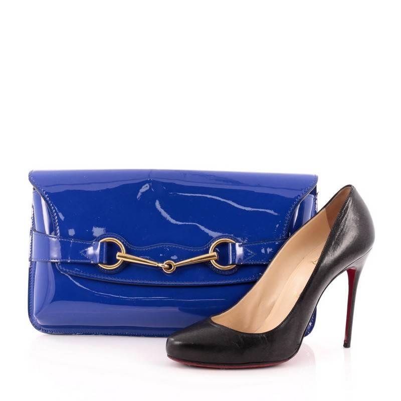 This authentic Gucci Bit Clutch Patent is a marvelous clutch for night outs. Crafted from vibrant blue patent leather, this stunning evening clutch features frontal gold horsebit detail, hand painted edges. Its flap opens to a sandy fabric-lined