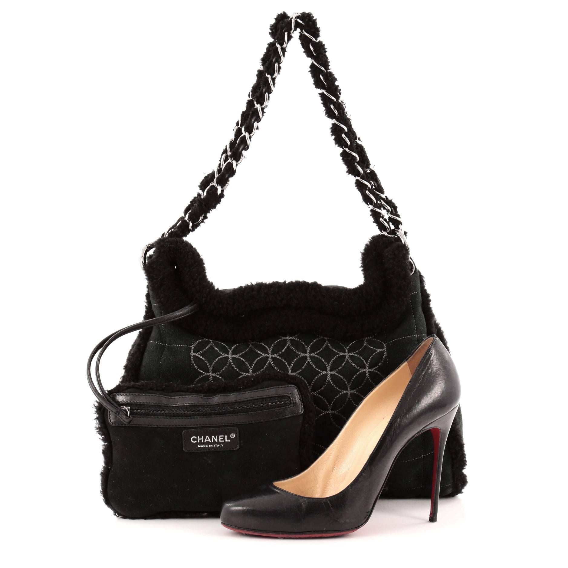 This authentic Chanel Embroidered CC Chain Tote Quilted Suede and Shearling is made for the colder season. Crafted from black quilted suede and shearling trims, this stylish tote features woven-in shearling chain straps, CC stitched logo and