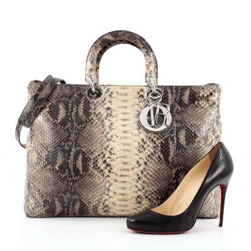 This authentic Christian Dior Lady Dior Handbag Python Large is an elegant and eye-catching piece made for the most daring of fashionistas. Crafted from creme and gray genuine python skin, this boxy, large tote features short dual handles, sleek