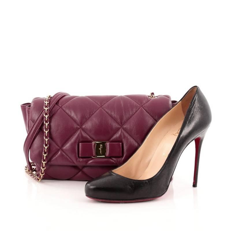 This authentic Salvatore Ferragamo Ginny Crossbody Bag Quilted Leather Medium mixes a classic design with youthful, feminine flair. Crafted from plum quilted leather, this crossbody features the stylish Vara-shoe bow design classic to the brand with