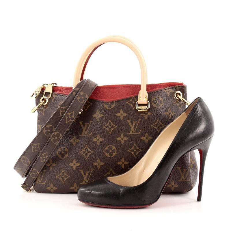 This authentic Louis Vuitton Pallas Tote Monogram Canvas BB released in 2014, is a mix of classic style with modern functionality. Crafted from brown monogram coated canvas with peeking supple red calfskin leather trim, this structured, petite
