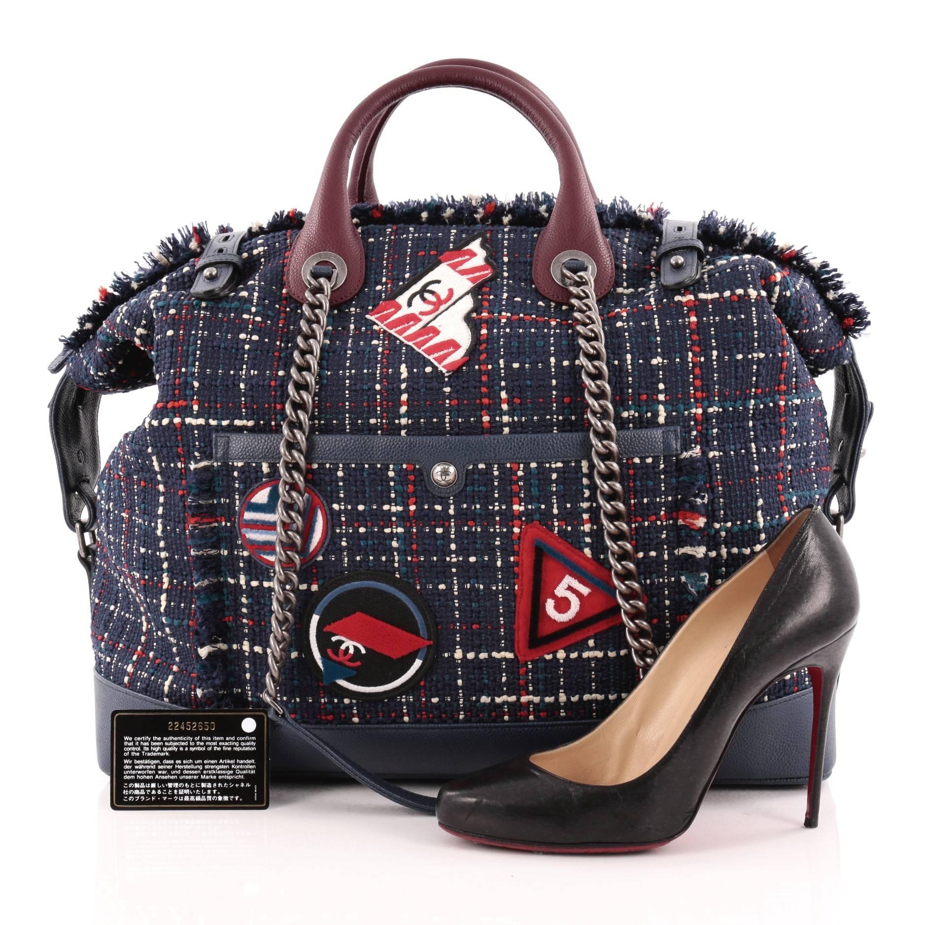 This authentic Chanel Crest Trip Bowling Bag Patch Embellished Tweed and Grained Calfskin Large presented in the brand's Spring/Summer 2016 Act II Collection is a luxurious travel piece to glam up your casual look. Crafted in navy blue tweed with