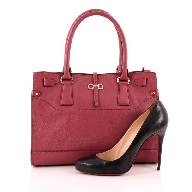 This authentic Salvatore Ferragamo Briana Tote Saffiano Leather Small is a classic tote that is a perfect addition to your wardrobe. Crafted from red saffiano leather, this stylish bag features dual-rolled leather handles, signature Gancini logo