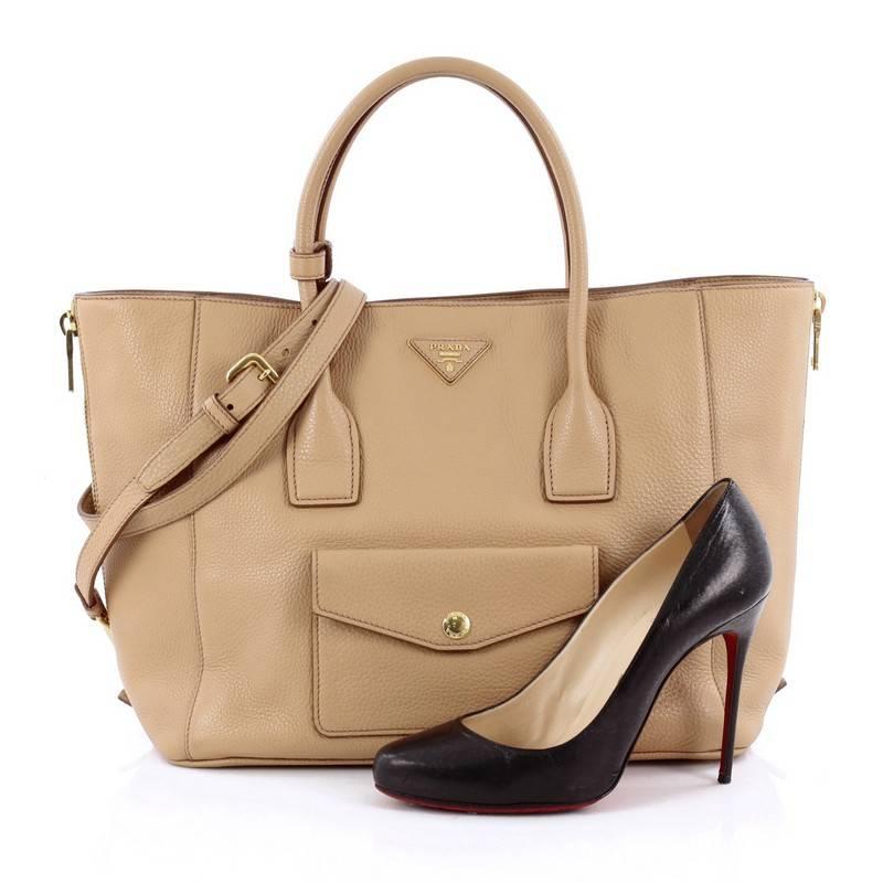 This authentic Prada Side Zip Convertible Tote Vitello Daino is elegant in its simplicity and structure. Crafted from beautiful beige vitello daino leather, this stylish yet functional tote features dual-rolled top handles, raised Prada Milano logo