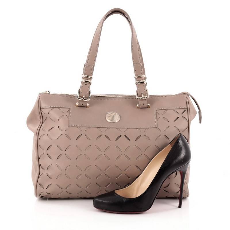 This authentic Versace Belted Handle Tote Laser Cut Leather Large is luxurious and sophisticated in design perfect for everyday use. Crafted from taupe laser cut leather, this chic bag features adjustable dual flat leather handles, engraved logo