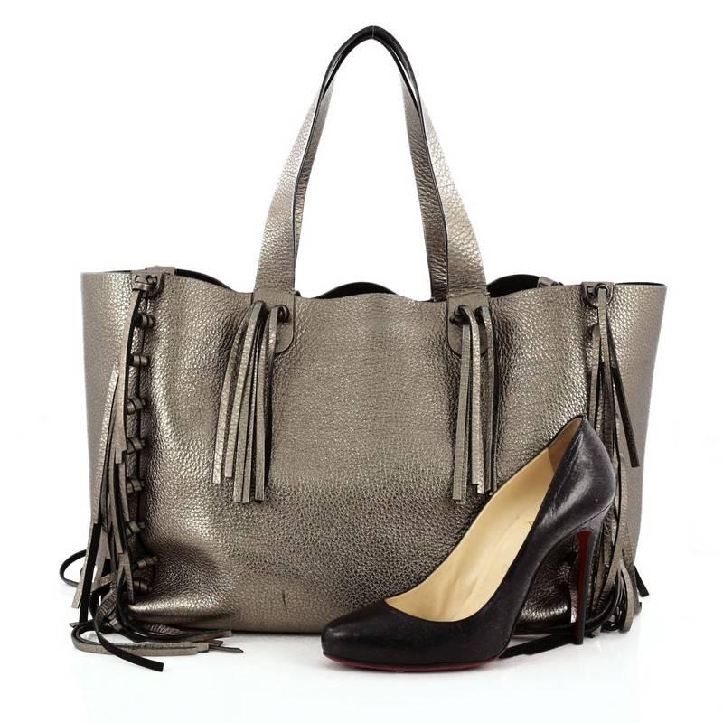 This authentic Valentino C-Rockee Fringe Tote Leather Medium presented in its Spring/Summer 2014 Collection mixes the brand's penchant for bohemian style with modern, chic flair made for any fashionista. Crafted from metallic silver pebbled leather,