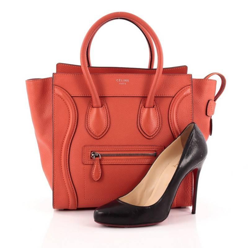 This authentic Celine Luggage Handbag Grainy Leather Micro is one of the most sought-after bags beloved by fashionistas. Crafted from red orange grainy leather, this minimalist tote features dual-rolled handles, an exterior front pocket, protective