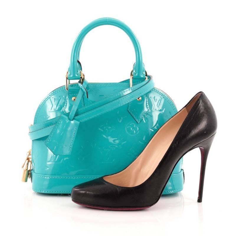This authentic Louis Vuitton Alma Handbag Monogram Vernis BB is a fresh and elegant spin on a classic style that is perfect for all seasons. Crafted from Louis Vuitton's glossy monogram vernis leather in beautiful bleu lagon teal, this dome-shaped
