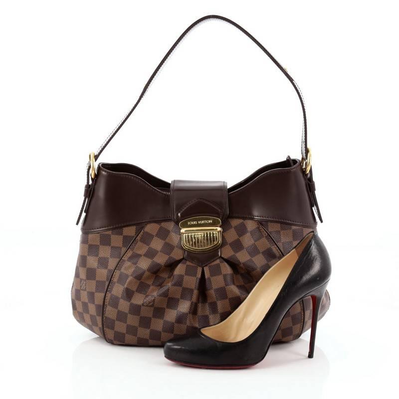 This authentic Louis Vuitton Sistina Handbag Damier MM is perfect for everyday use. Crafted from damier ebene coated canvas, this stylish, feminine bag features center pleating, smooth brown leather trims, flat buckle shoulder straps, and gold-tone