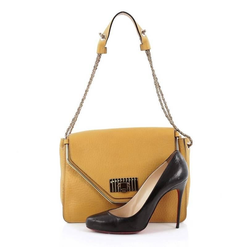 This authentic Chloe Sally Shoulder Bag Leather Medium showcases a simple yet sleek silhouette with dramatic flair. Crafted from mustard grainy leather, this chic, elegant flap features a gold-tone frame, chain link strap, protective base studs and