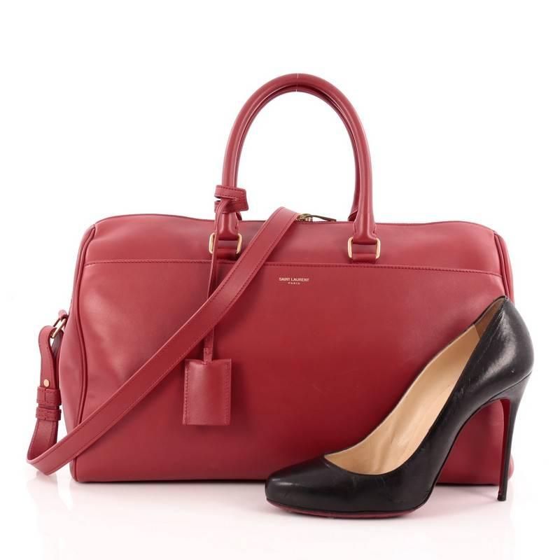 This authentic Saint Laurent Classic Duffle Bag Leather 12 is a sleek, modern and an elegant duffle bag to travel in style with. Crafted with red leather, this alluring bag features dual-rolled leather handles and detachable strap that can be