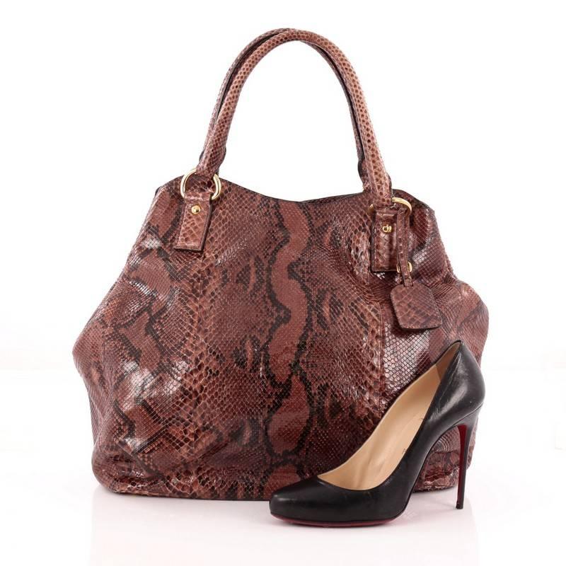 This authentic Prada Shoulder Bag Python XL is a luxurious, eye-catching and one-of-a-kind piece. Crafted in genuine brown python skin, this oversized tote features dual-rolled handles, leather tag, side snap buttons, protective base studs and