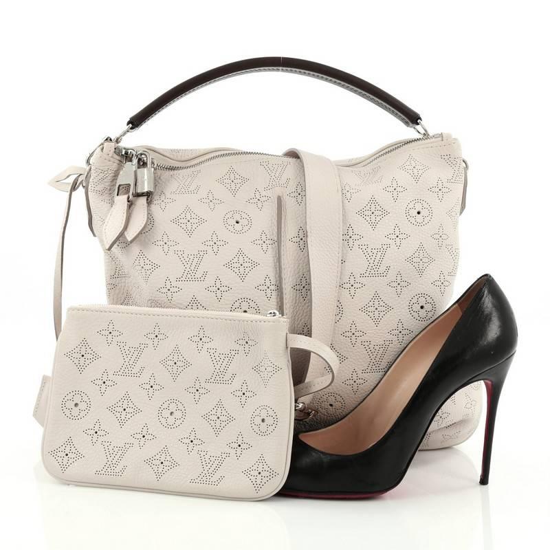 This authentic Louis Vuitton Selene Handbag Mahina Leather PM is an easy, feminine design showcased in the brand's Spring/ Summer 2013 Collection. Constructed with intricate perforated LV monogram in beautiful, airy off-white mahina leather, this