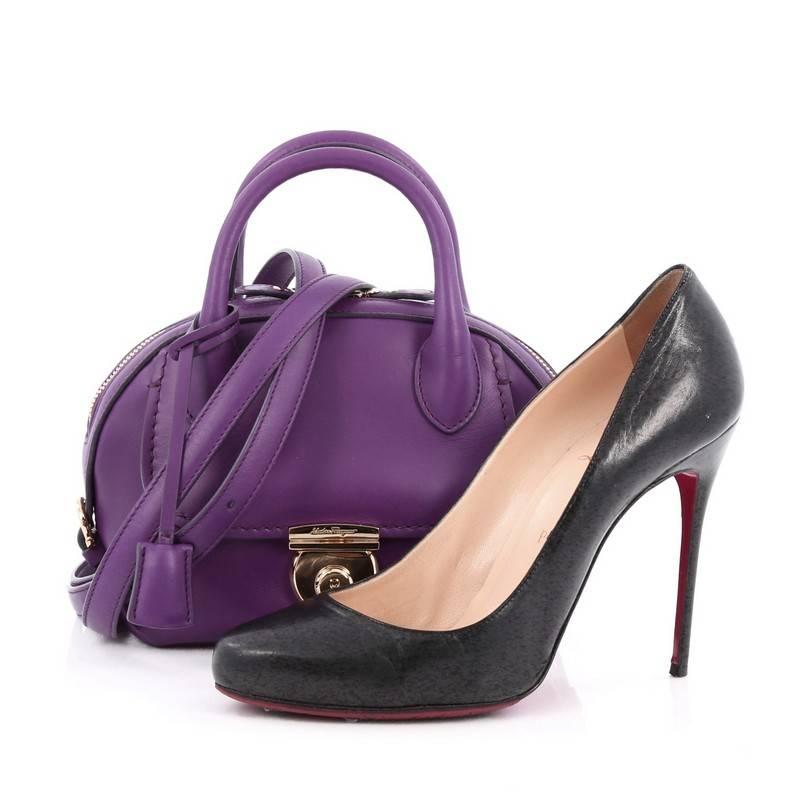 This authentic Salvatore Ferragamo Fiamma Satchel Leather Mini an ode to the classic 1990's Ferragamo design, is sophisticated and elegant. Crafted from purple leather, this heritage-inspired mini dome satchel features a front flap pocket with lock