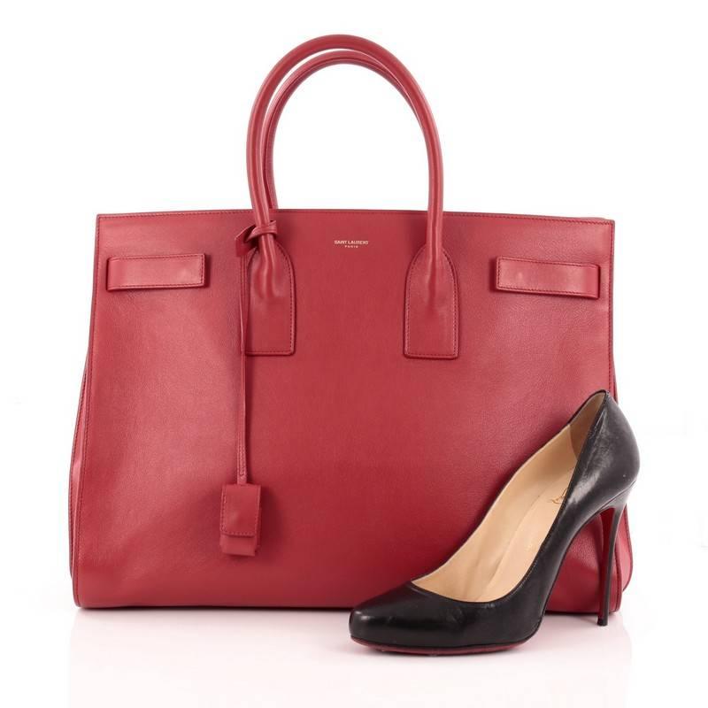 This authentic Saint Laurent Sac De Jour Handbag Leather Large is a sleek yet elegant bag synonymous with the brand's classic aesthetics. Crafted from red leather, this sought-after tote features a gold Saint Laurent stamped signature at the front,