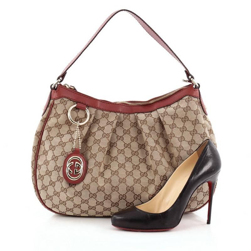 This authentic Gucci Sukey Hobo GG Canvas Medium is perfect for any casual or sophisticated outfit. Constructed from Gucci's brown GG monogram canvas with maroon red leather trims, this simple hobo features a flat leather strap that sit comfortably