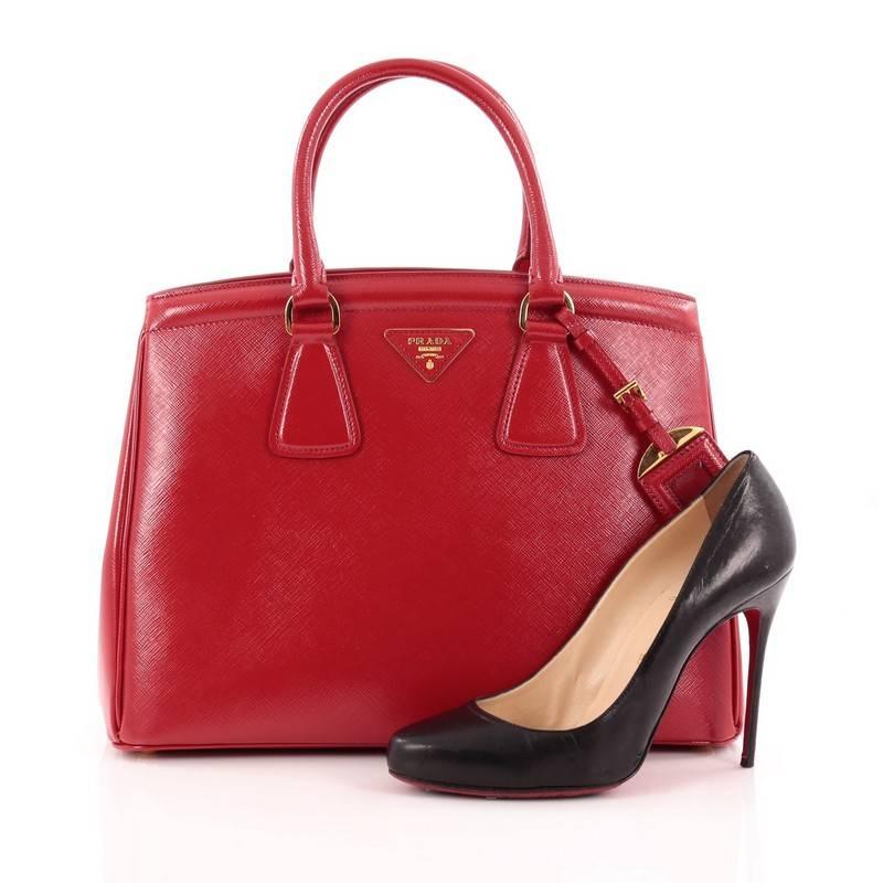 This authentic Prada Parabole Handbag Vernice Saffiano Leather is elegant in its simplicity and structure. Constructed in rosso red vernice saffiano leather, this sleek tote features dual-rolled leather handles, raised Prada logo, protective base