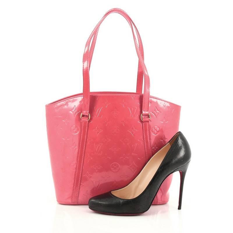 This authentic Louis Vuitton Avalon Handbag Monogram Vernis MM is a fresh and elegant spin on a classic style that is perfect for all seasons. Crafted from Louis Vuitton's pink monogram vernis leather, this fan-shaped tote features dual flat