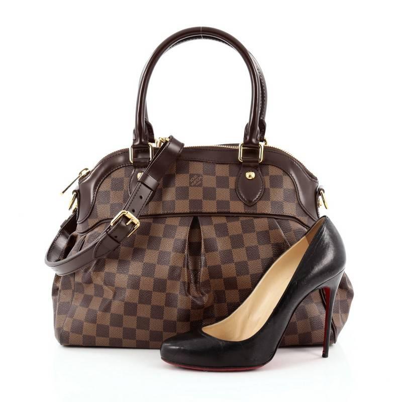 This authentic Louis Vuitton Trevi Handbag Damier PM inspired by the Trevi Fountain is a chic and versatile handle bag. Crafted from classic damier ebene coated canvas, this tote features dual-rolled handles, brown leather trims, subtle pleats in