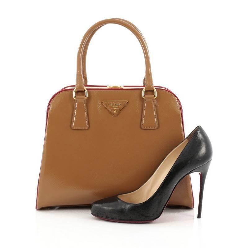 This authentic Prada Pyramid Top Handle Bag Vernice Saffiano Leather Medium is sophisticated and luxurious in design perfect for everyday use. Crafted in brown vernice saffiano leather, this bag features red vernice saffiano leather trims, eggshell