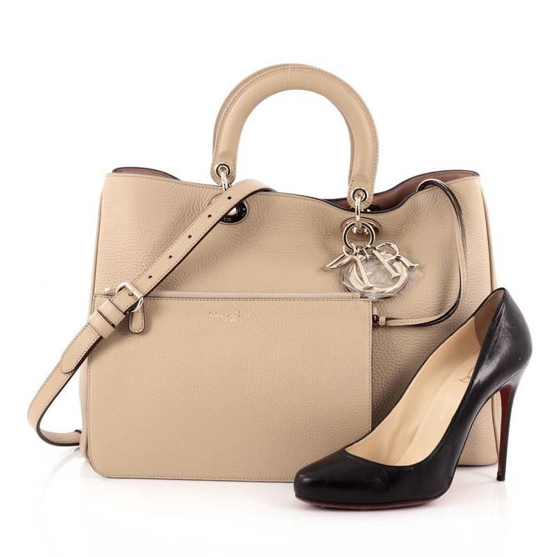 This authentic Christian Dior Diorissimo Tote Pebbled Leather Large is an elegant, classic statement piece that every fashionista needs in her wardrobe. Crafted from biege pebbled leather, this chic tote features smooth short dual handles with sleek