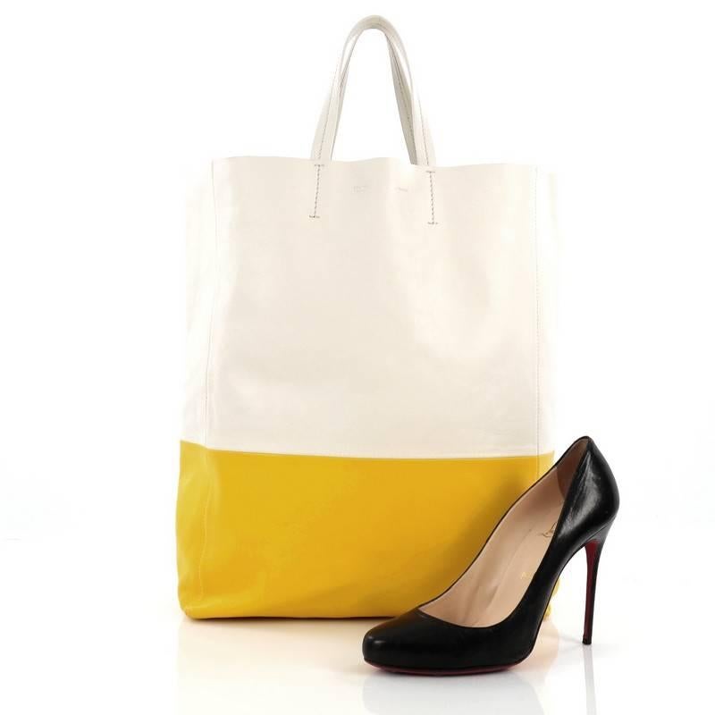 This authentic Celine Vertical Bi-Cabas Tote Leather Large is a perfect everyday accessory for the woman on-the-go. Crafted in minimalistic bi-color yellow and white leather, this no-fuss tall tote features slim top handles and gold-tone hardware