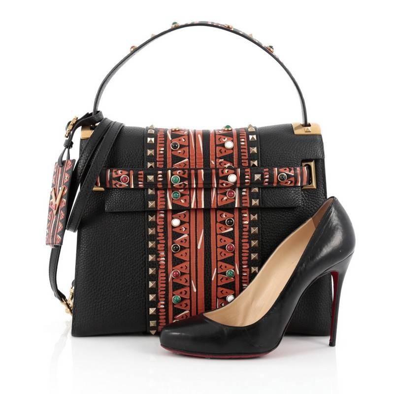 This authentic Valentino My Rockstud Convertible Satchel Tribal Embellished Leather Medium displays a tribal design perfect for bold fashionistas. Crafted in black leather with tribal pattern embellishments, this bag features single loop leather