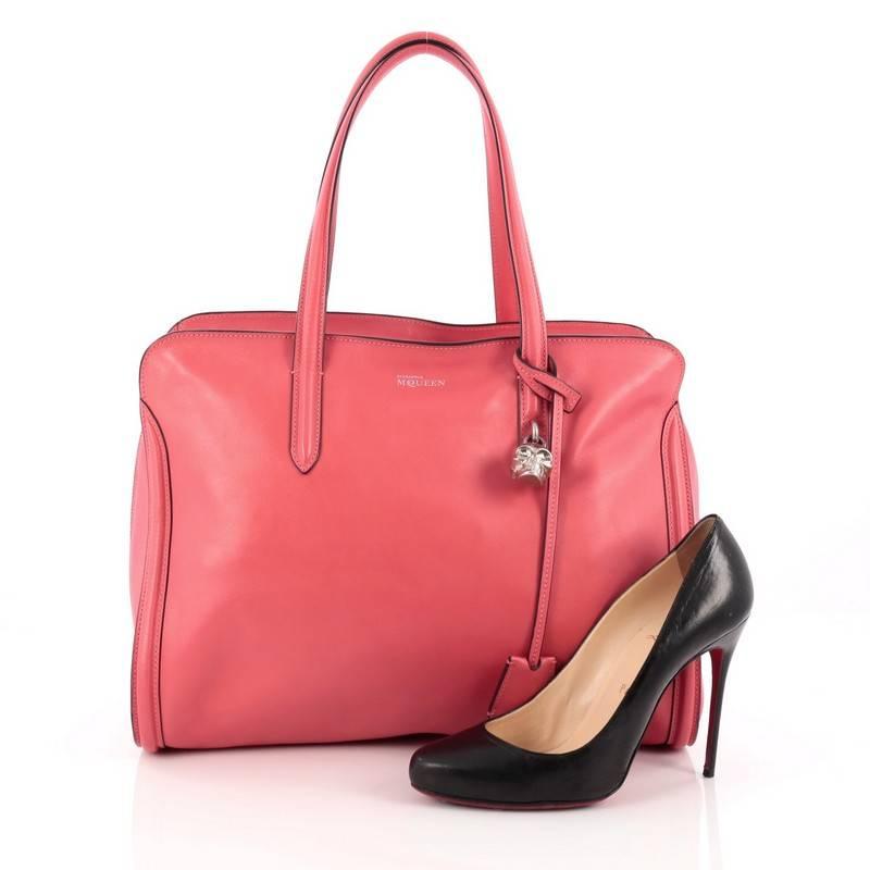 This authentic Alexander McQueen Padlock Zip Around Tote Leather Medium is a sleek and stylish accessory made for every fashionista. Crafted in pink leather, this functional tote features dual leather handles, defined edges, signature silver skull