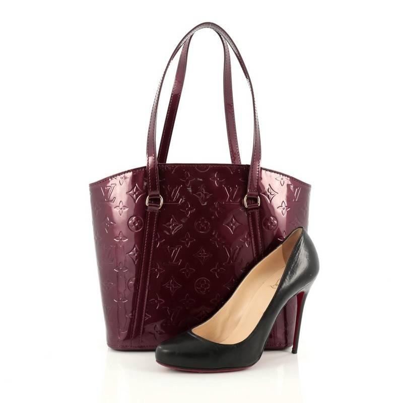This authentic Louis Vuitton Avalon Handbag Monogram Vernis MM is a fresh and elegant spin on a classic style that is perfect for all seasons. Crafted from Louis Vuitton's rouge fauviste monogram vernis leather, this fan-shaped tote features dual