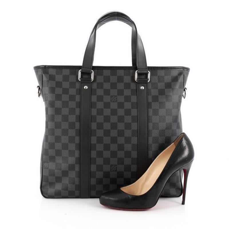 This authentic Louis Vuitton Tadao Handbag Damier Graphite PM is a highly versatile and sophisticated tote made for the style-conscious man or woman. Crafted from damier graphite canvas, this luxurious on-the-go tote features dual-flat leather