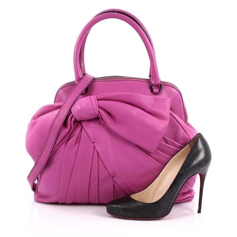 This authentic Valentino Bow Bondage Bag Nappa Leather is a playful and chic design made for casual use. Constructed in vibrant fuchsia nappa leather, this feminine yet fun satchel features Valentino's signature oversized bow design, pleated leather