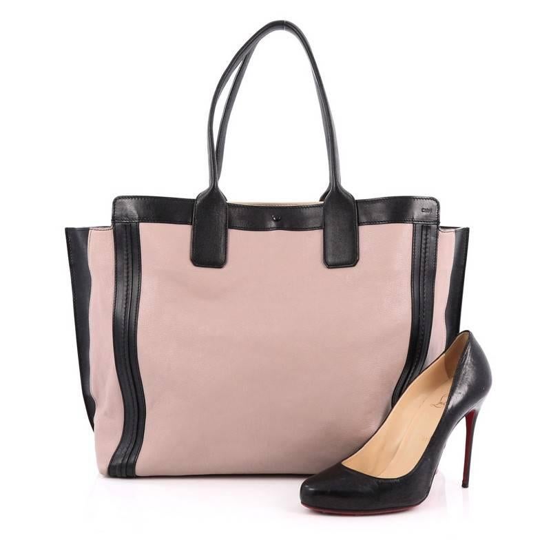 This authentic Chloe Alison East West Tote Leather Large is perfect for an everyday bag. Constructed from mauve and black leather, this simple, functional tote features dual-rolled handles with winged sides. Its magnetic clasp closure opens to a