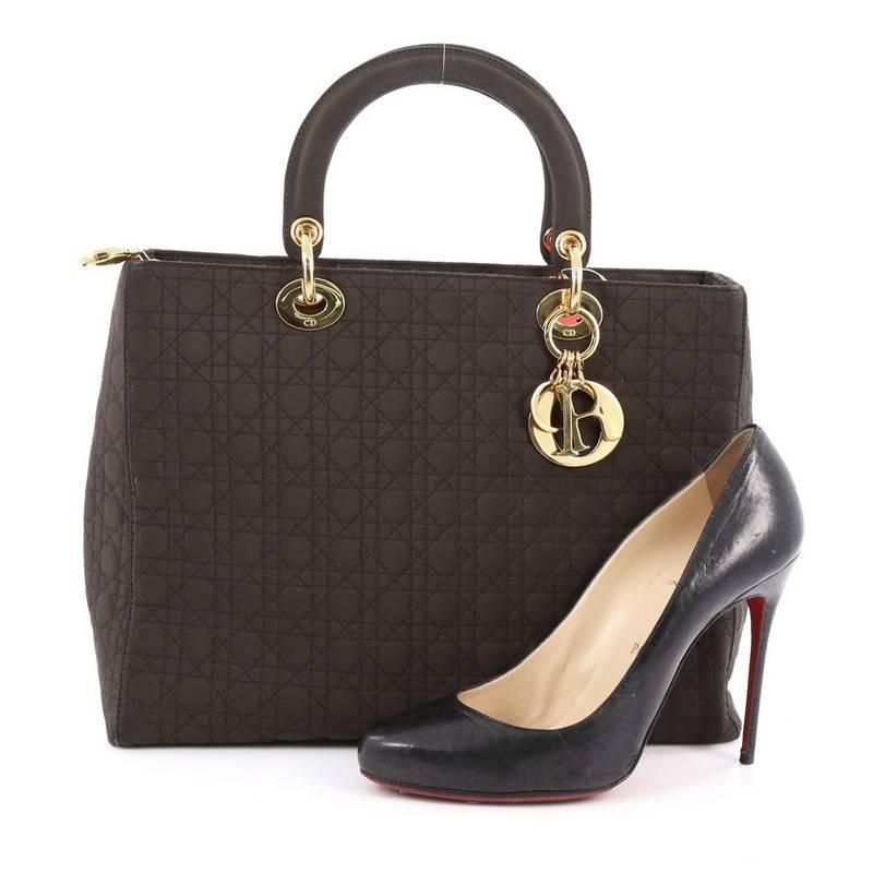 This authentic Christian Dior Lady Dior Handbag Cannage Quilt Nylon Large is a classic staple that every fashionista needs in her wardrobe. Crafted from dark brown nylon in Dior's iconic cannage quilting, this boxy bag features dual-rolled handles