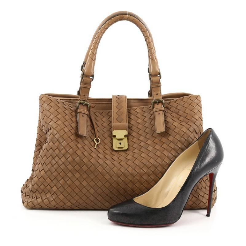 This authentic Bottega Veneta Roma Handbag Intrecciato Nappa Medium in brown is a finely crafted tote that exudes an understated elegance. Crafted from leather woven in Bottega Veneta's signature intrecciato method, it features push lock tab opening