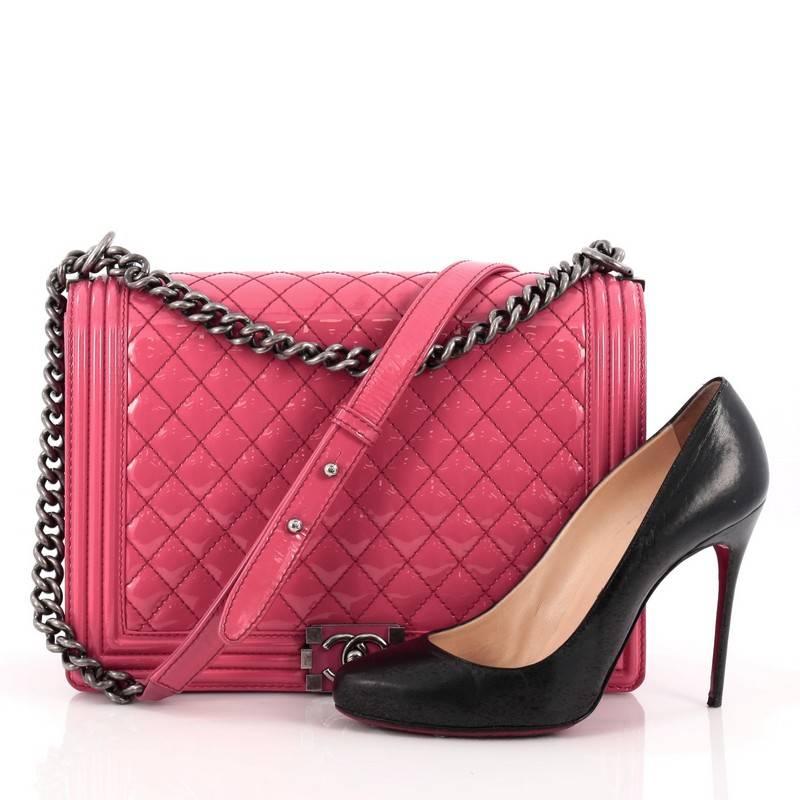 This authentic Chanel Boy Flap Bag Quilted Patent Large is every woman's dream. Crafted from luxurious fuchsia diamond quilted patent leather, this popular, enviable Boy flap bag features a chunky chain link strap with leather shoulder pad, iconic