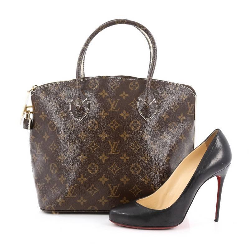 This authentic Louis Vuitton Lockit Handbag Monogram Fetish Canvas released during Fall/Winter 2011/2012 plays on structured design with a modern flair showcasing its iconic Lockit model. Crafted in Louis Vuitton's updated brown monogram canvas with
