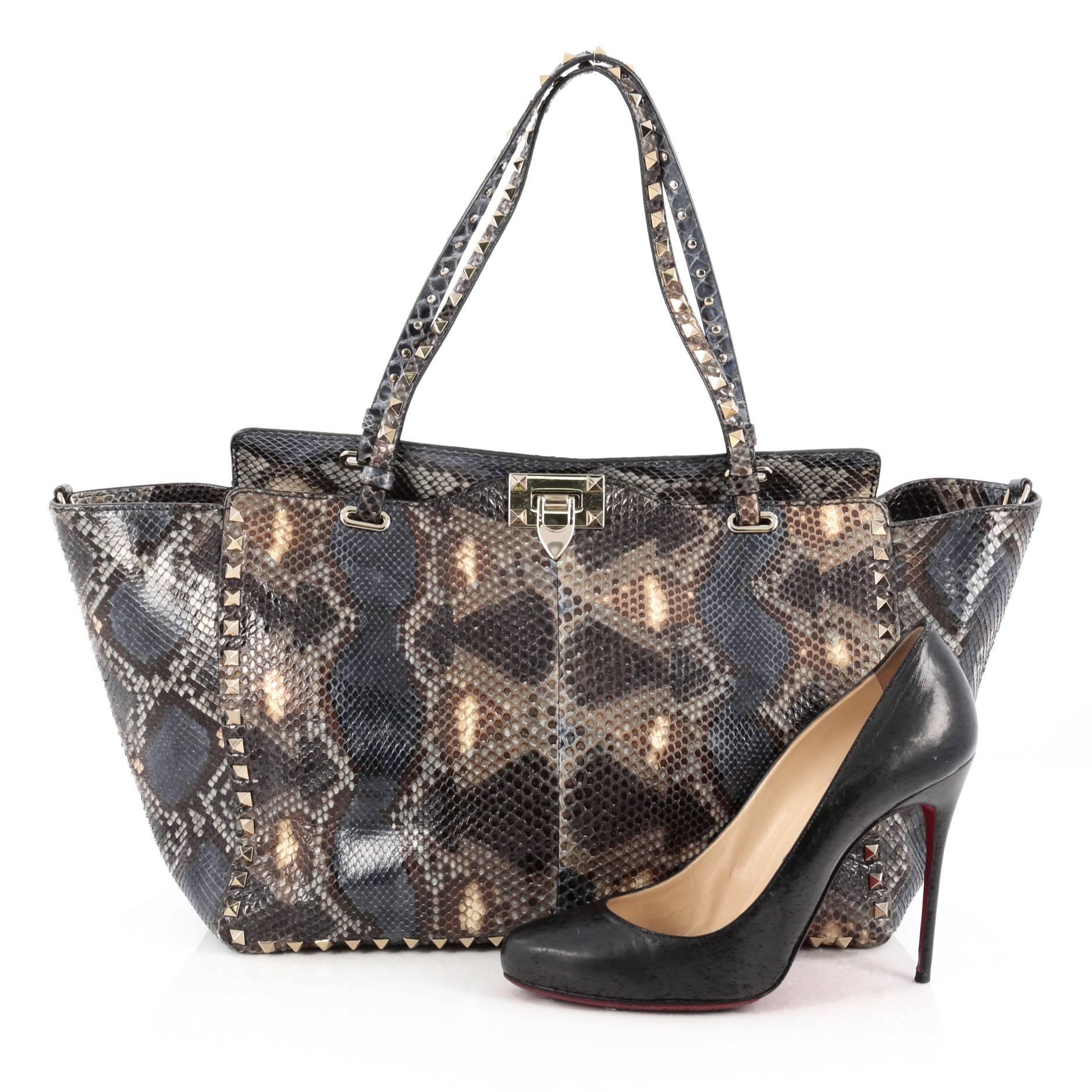 This authentic Valentino Rockstud Tote Python Large is a stylish and iconic bag that is one of today's most sought-after styles. Crafted from genuine multicolor python, this chic tote features tall dual-flat handles, gold-tone pyramid stud trim