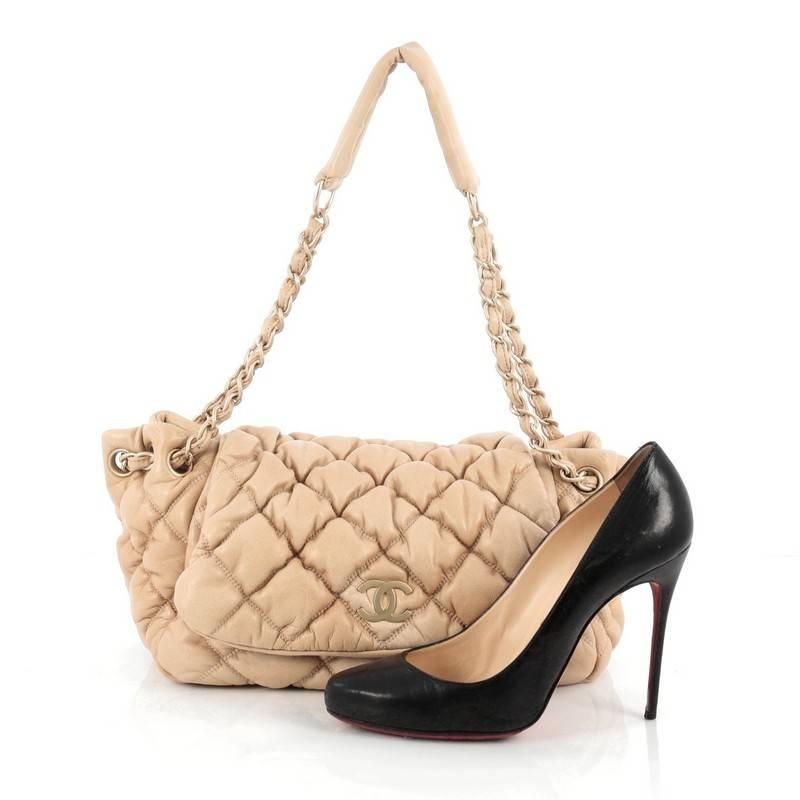 This authentic Chanel Bubble Accordion Flap Bag Quilted Lambskin Medium is sure to complement just about every casual outfit. Crafted in beige bubble quilted leather, this soft, puffy flap bag features woven-in leather chain strap threaded through
