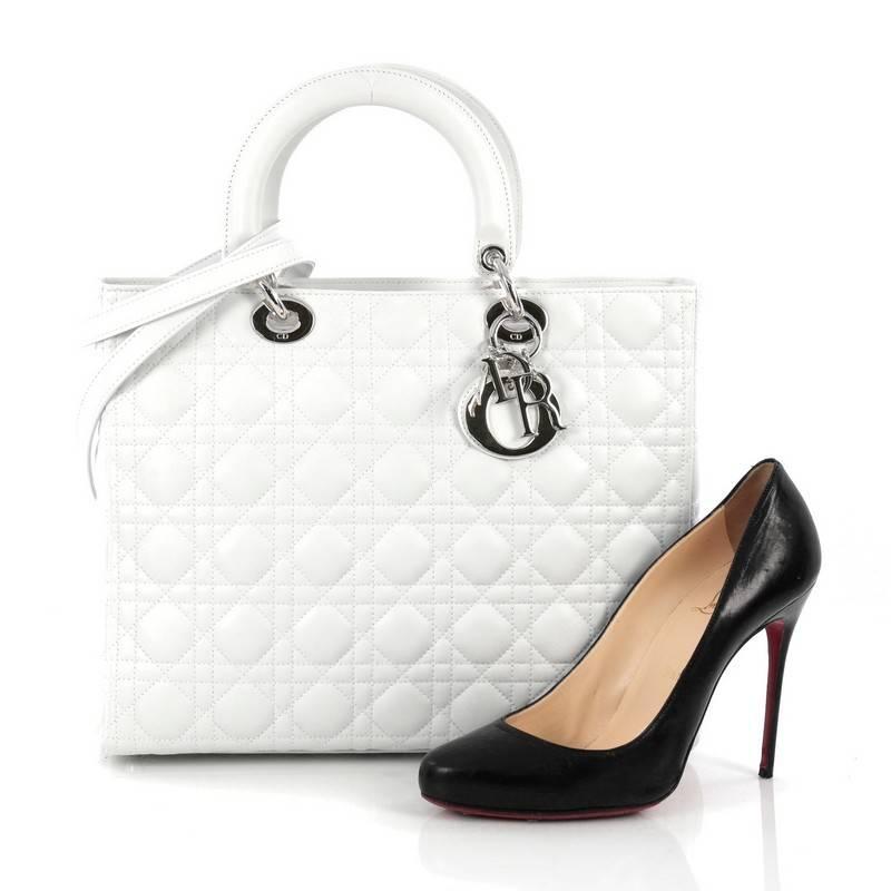 This authentic Christian Dior Lady Dior Handbag Cannage Quilt Lambskin Large is a classic staple that every fashionista needs in her wardrobe. Crafted from white lambskin leather in Dior's iconic cannage quilting, this boxy bag features dual-rolled