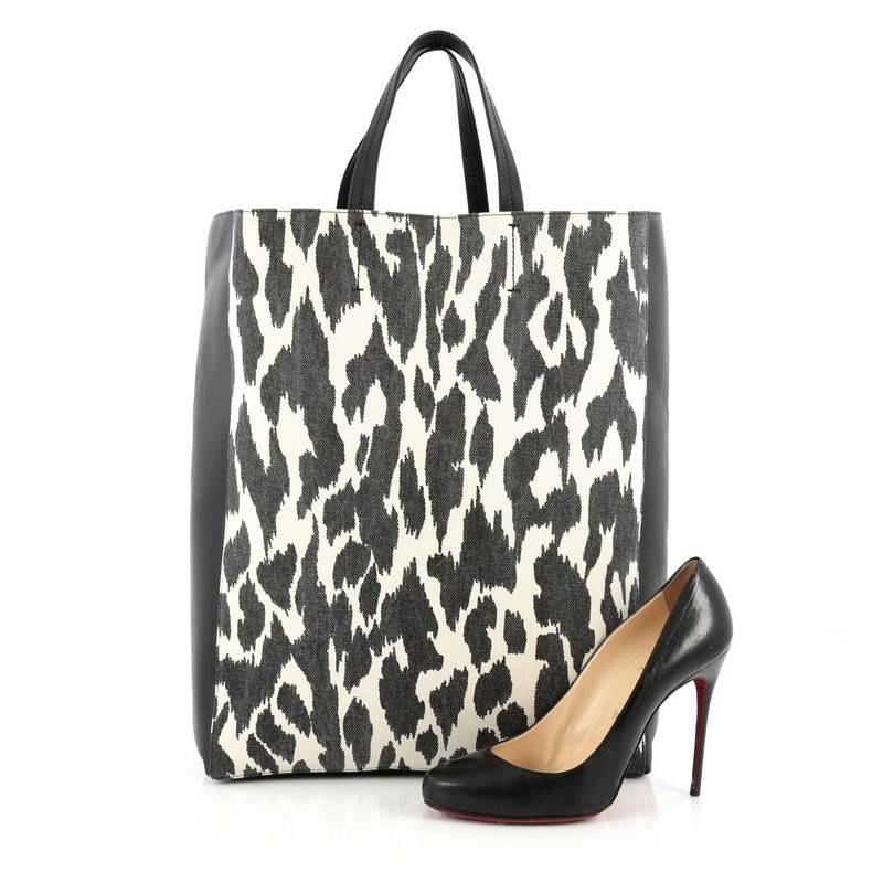 This authentic Celine Vertical Bi-Cabas Tote Printed Canvas and Leather Large is a perfect everyday accessory for the woman on-the-go. Crafted in black leather with animal print canvas, this no-fuss tall tote features slim top handles and gold-tone