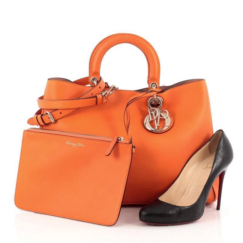 This authentic Christian Dior Diorissimo Tote Pebbled Leather Large is an elegant, classic statement piece that every fashionista needs in her wardrobe. Crafted from orange leather, this chic tote features smooth short dual handles with sleek Dior