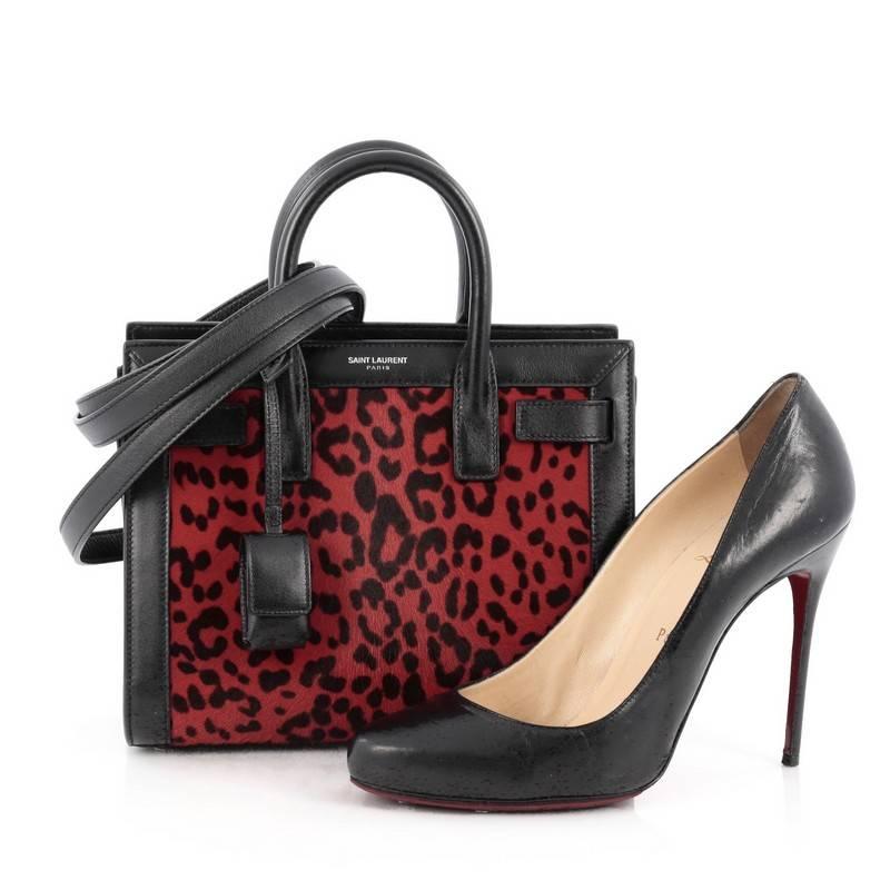 This authentic Saint Laurent Sac De Jour Handbag Printed Calf Hair Nano is a sleek yet elegant bag synonymous with the brand's classic aesthetic. Crafted from genuine red leopard printed calf hair and black leather, this sought-after structured