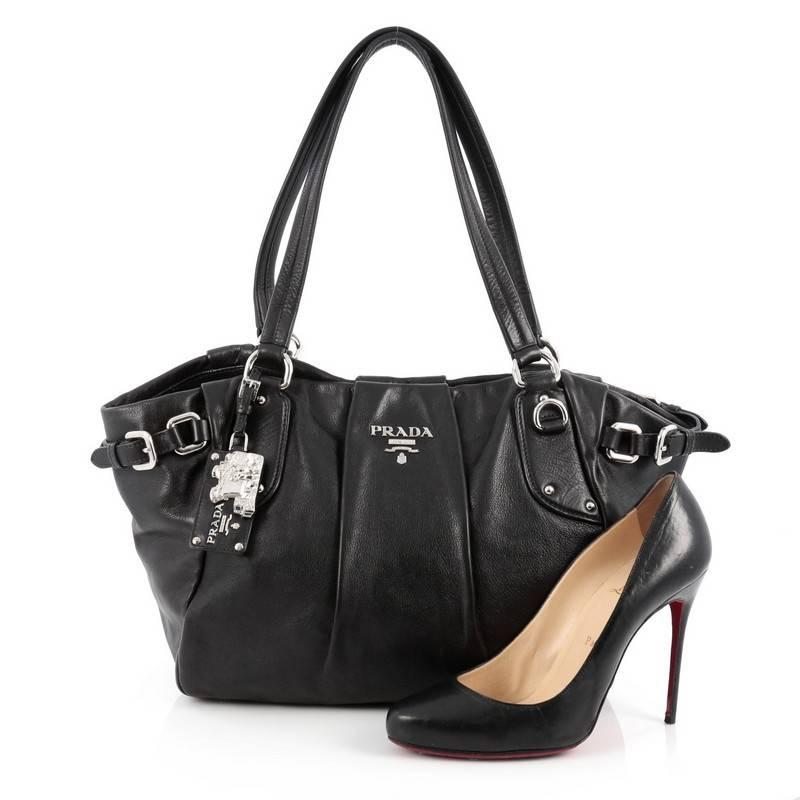 This authentic Prada Belted Tote Pleated Leather Medium is ideal for everyday use. Crafted in black pleated leather, this bag features a dual flat leather strap, buckle detailing, raised Prada logo, protective base studs and silver-tone hardware