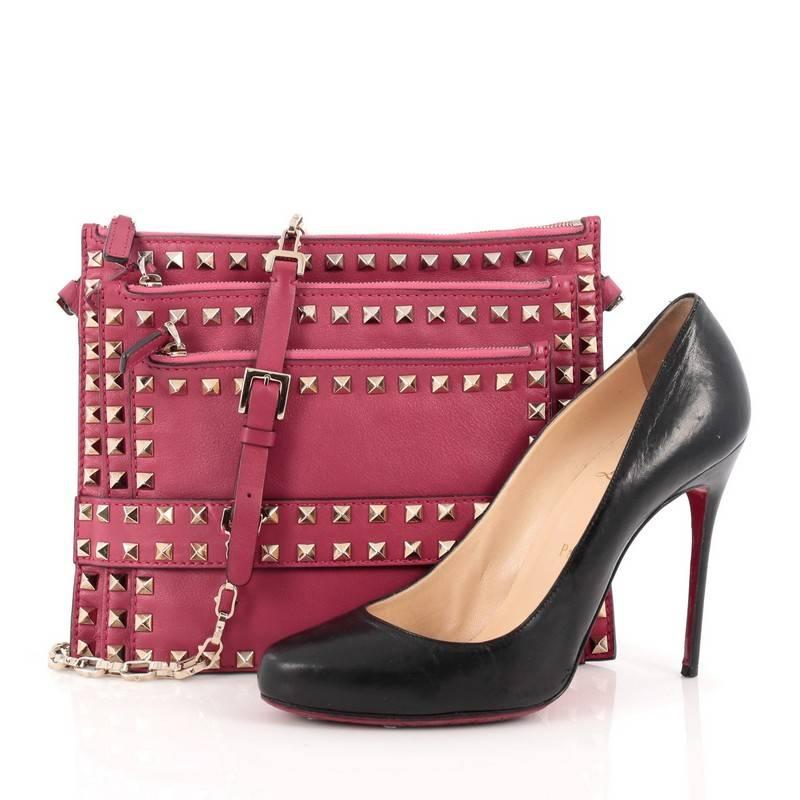 This authentic Valentino Rockstud Triple Zip Clutch Leather is an absolutely gorgeous bag that is a must have for every fashionista. Crafted from dark pink leather, this clutch features chain-link crossbody strap with belted leather inset, signature